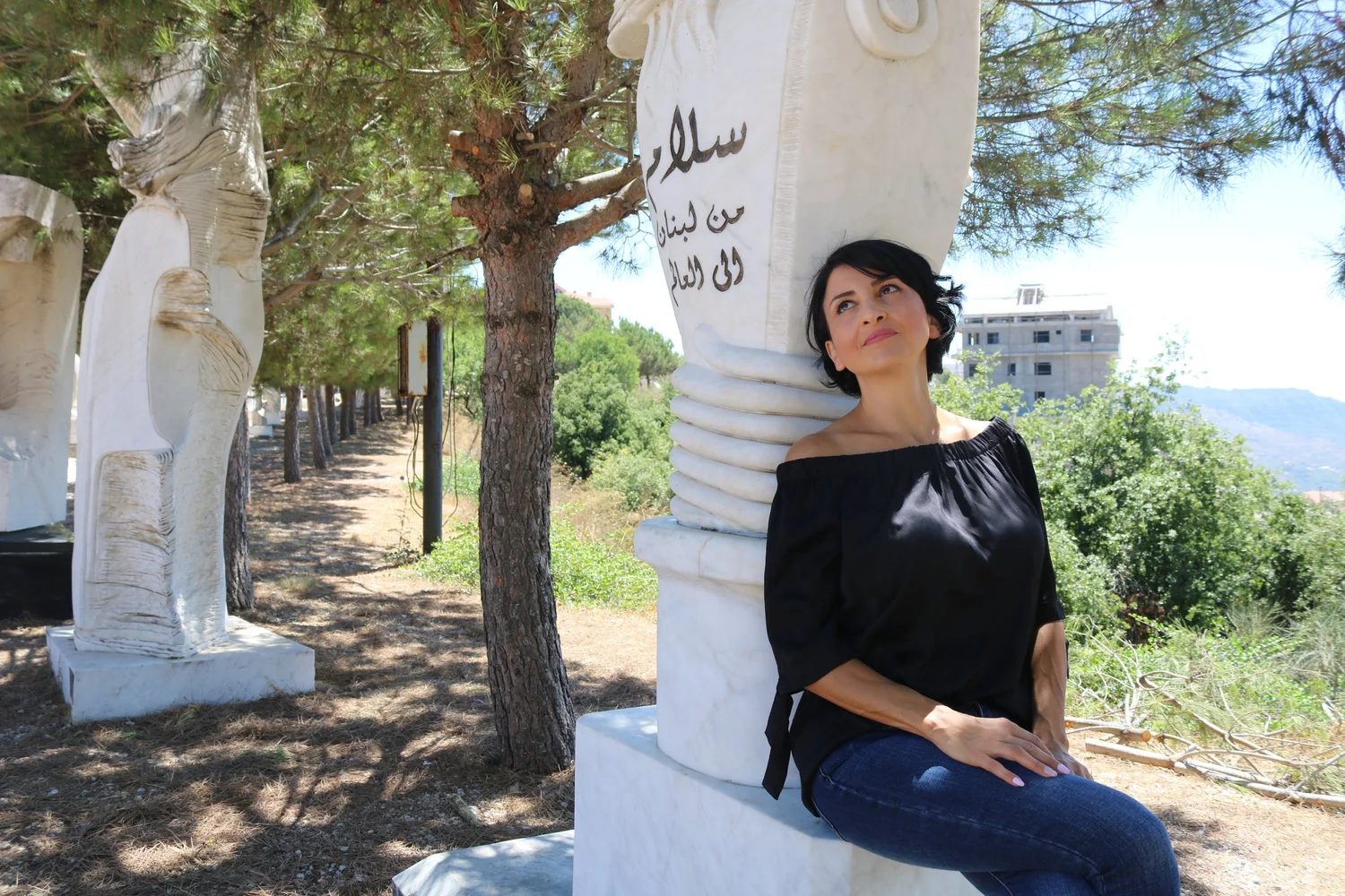 Dr. Jomana Elaridi seated beside a sculpture in Lebanon
